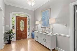 foyer entrance featuring ornamental molding and light wood finished floors