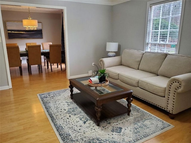 living area with ornamental molding, light wood finished floors, and baseboards