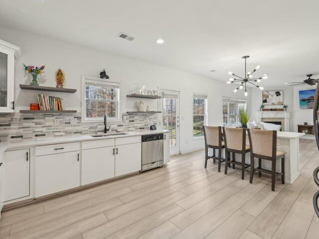 kitchen with a healthy amount of sunlight, open shelves, a sink, dishwasher, and backsplash