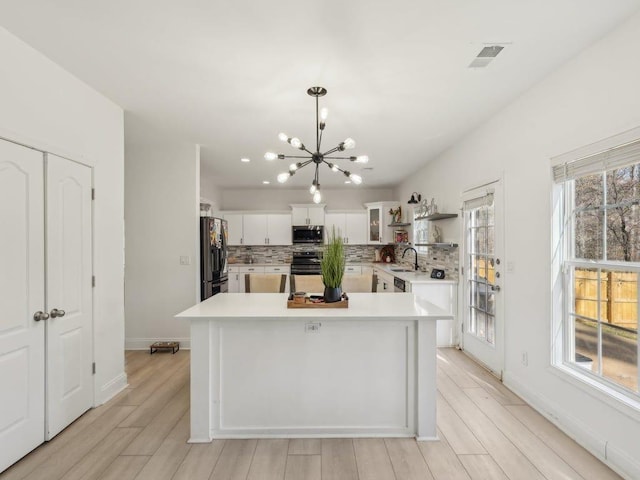 kitchen featuring decorative backsplash, light countertops, white cabinets, appliances with stainless steel finishes, and a chandelier
