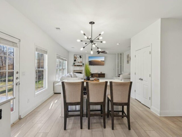 dining area with an inviting chandelier, baseboards, and light wood-type flooring