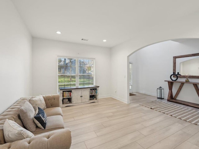 living area with visible vents, recessed lighting, light wood-style floors, and arched walkways
