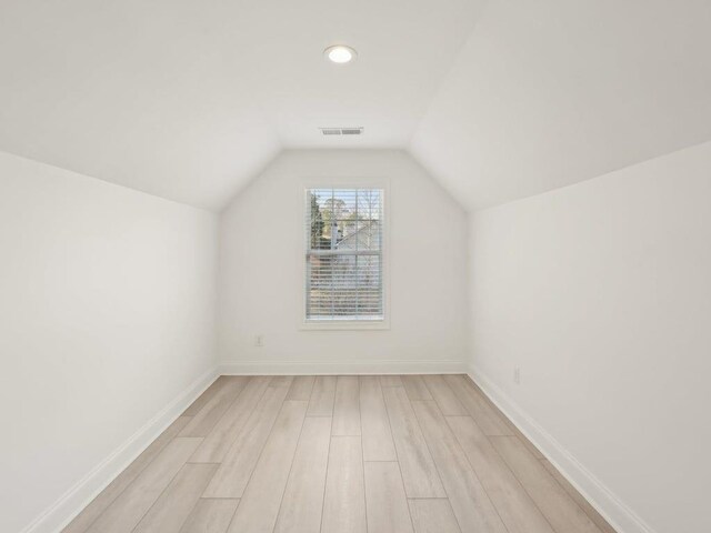 additional living space with visible vents, baseboards, light wood-style floors, and lofted ceiling