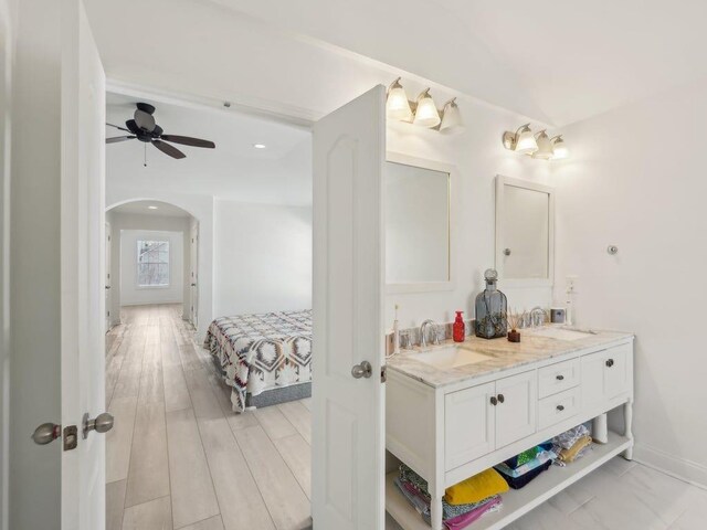 full bath with a sink, baseboards, ceiling fan, and double vanity