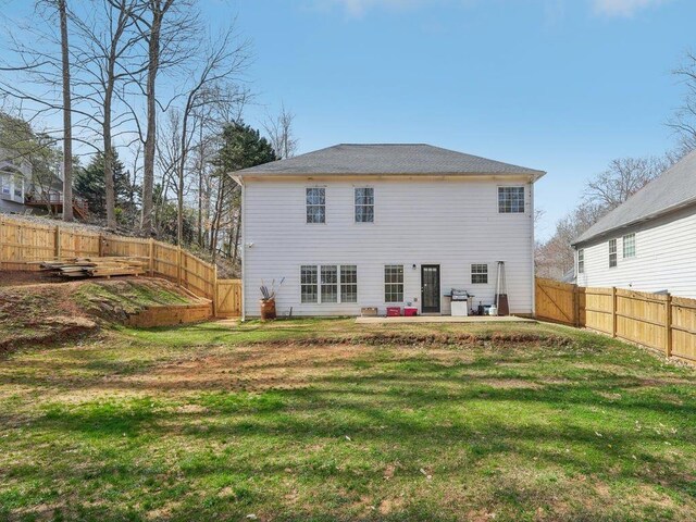 rear view of house featuring a patio area, a yard, and a fenced backyard