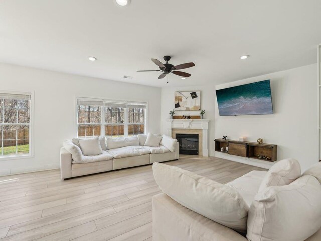 living room with a premium fireplace, recessed lighting, light wood-style floors, and ceiling fan