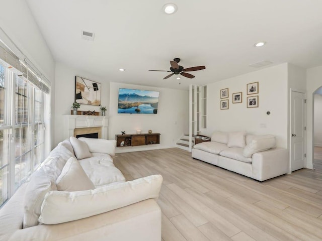 living area with light wood finished floors, visible vents, ceiling fan, recessed lighting, and a fireplace