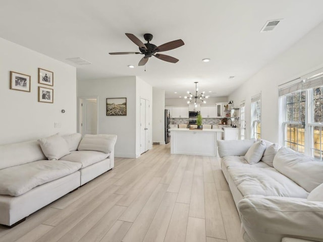 living area featuring recessed lighting, visible vents, light wood-style floors, and ceiling fan with notable chandelier