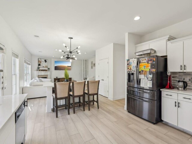 kitchen featuring light wood finished floors, light countertops, white cabinetry, fridge with ice dispenser, and a chandelier