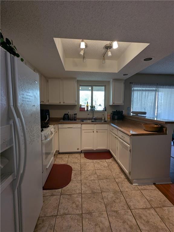 kitchen with white cabinets, white appliances, sink, and a tray ceiling