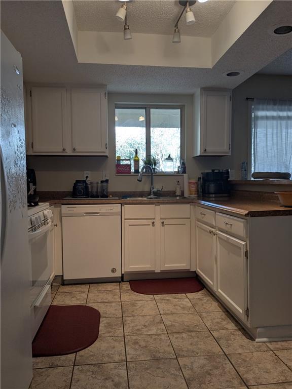 kitchen featuring white cabinetry, rail lighting, and white appliances