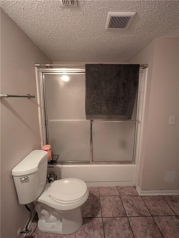 bathroom featuring tile patterned flooring, a textured ceiling, toilet, and combined bath / shower with glass door