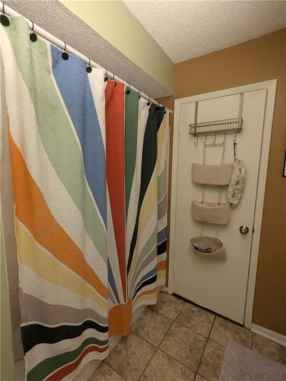 bathroom with a textured ceiling and tile patterned floors