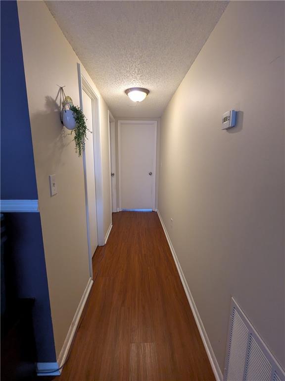 hallway featuring wood-type flooring and a textured ceiling