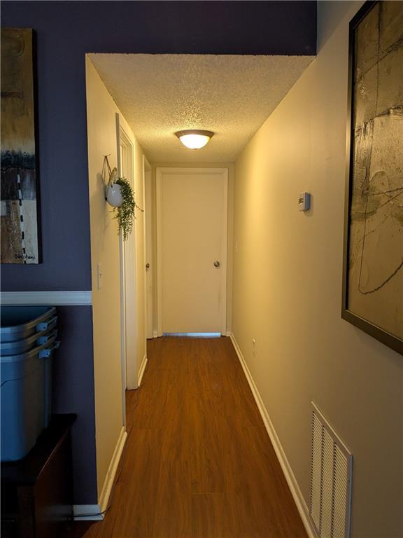 hall featuring a textured ceiling and dark wood-type flooring