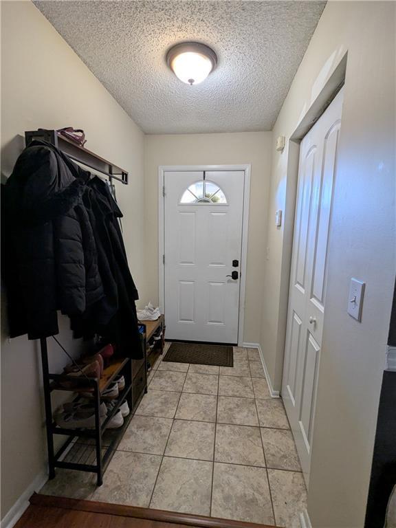 doorway featuring a textured ceiling and light tile patterned flooring