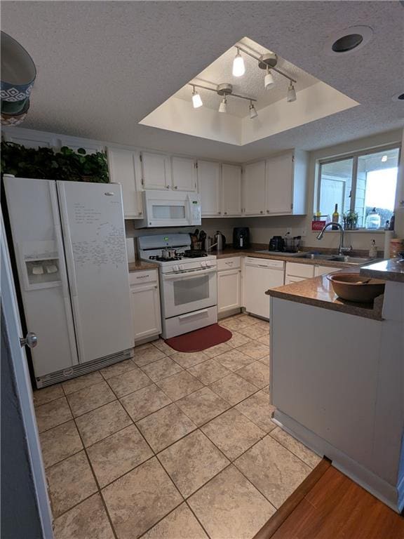 kitchen with white cabinetry, a tray ceiling, white appliances, a textured ceiling, and sink