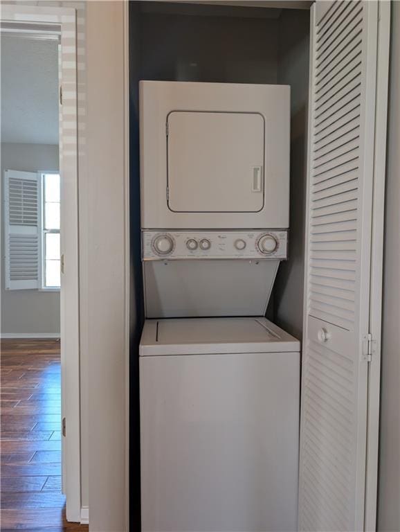 clothes washing area featuring stacked washing maching and dryer and dark hardwood / wood-style flooring