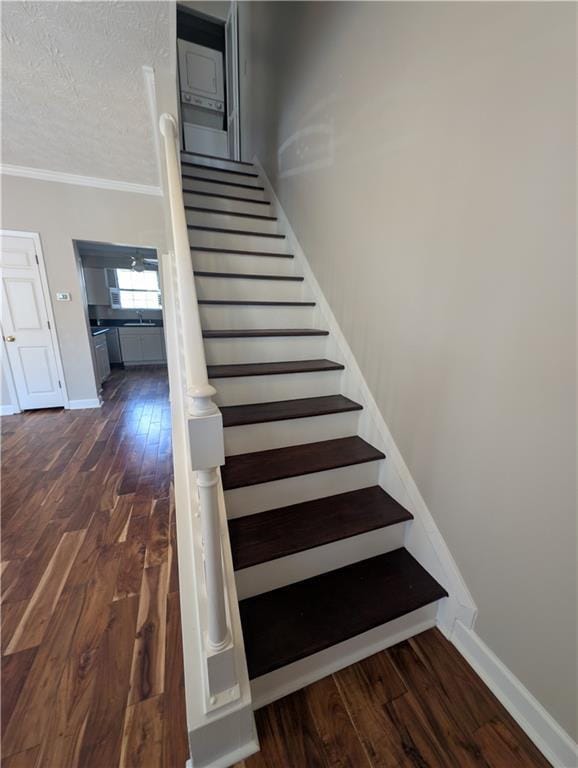 staircase featuring ornamental molding, hardwood / wood-style floors, and a textured ceiling