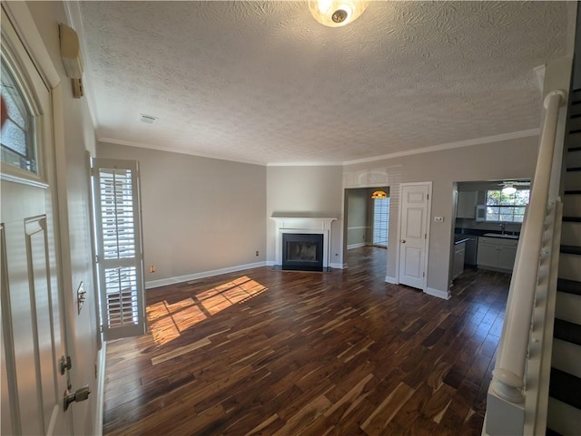 unfurnished living room featuring dark wood-type flooring, ornamental molding, sink, and a textured ceiling