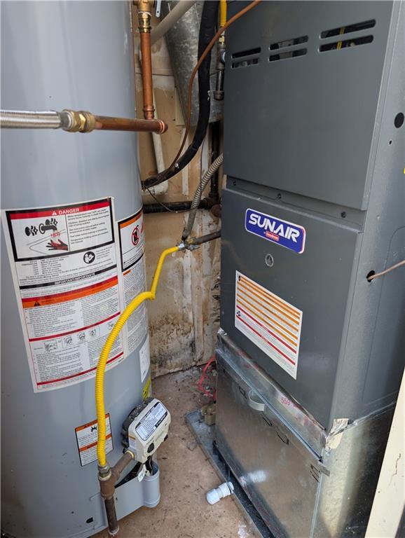 utility room featuring gas water heater and heating unit