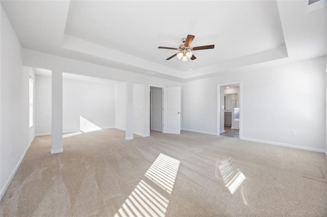 carpeted spare room with a raised ceiling and ceiling fan