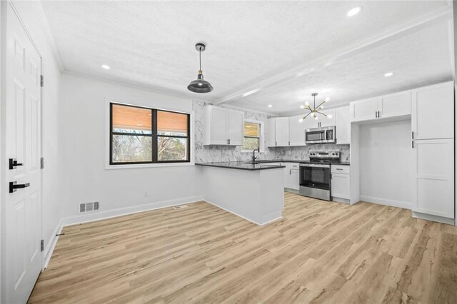 kitchen with appliances with stainless steel finishes, a textured ceiling, dark countertops, a sink, and white cabinetry