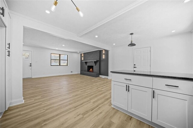 unfurnished living room with light wood-style flooring, a brick fireplace, recessed lighting, baseboards, and ornamental molding
