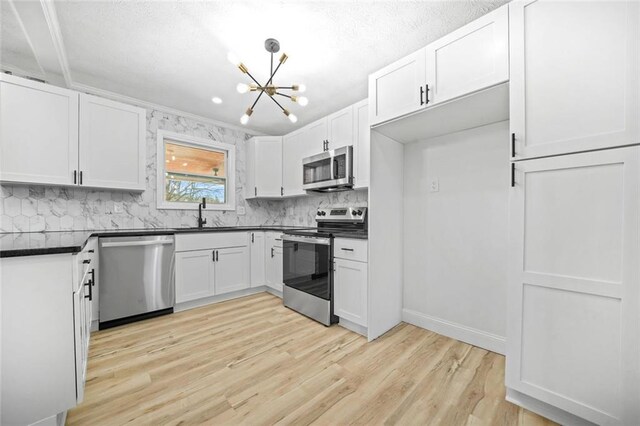 kitchen with stainless steel appliances, dark countertops, a chandelier, and decorative backsplash
