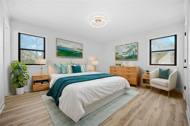 bedroom featuring light wood-type flooring, baseboards, and crown molding