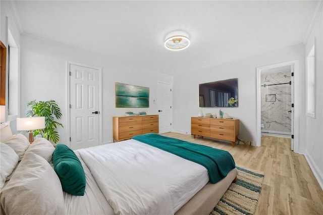 bedroom with light wood-type flooring, ornamental molding, baseboards, and ensuite bathroom