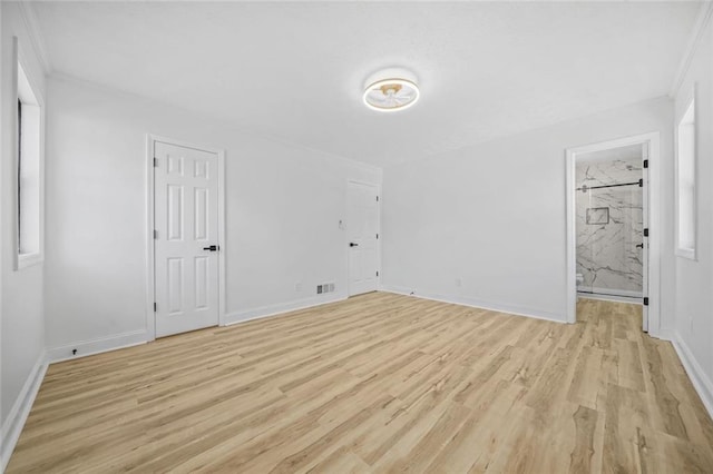 unfurnished bedroom with light wood-style floors, baseboards, crown molding, and connected bathroom
