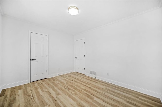 spare room featuring wood finished floors, ornamental molding, and baseboards