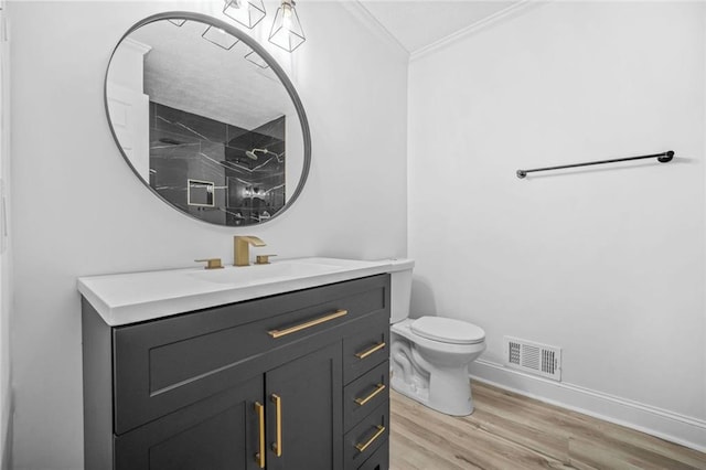 bathroom with ornamental molding, wood finished floors, baseboards, toilet, and vanity