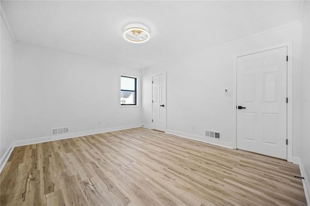 unfurnished room with light wood finished floors, baseboards, and crown molding