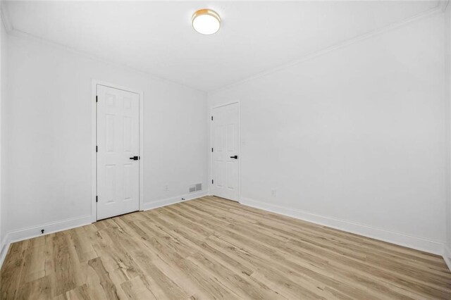 spare room featuring light wood-style flooring, crown molding, and baseboards