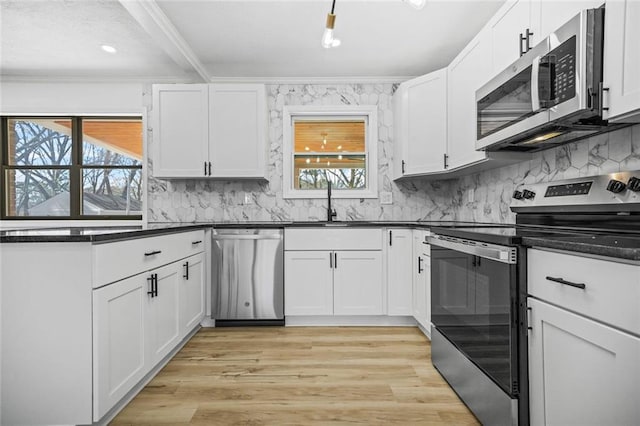 kitchen with appliances with stainless steel finishes, dark countertops, a sink, decorative backsplash, and ornamental molding
