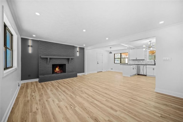 unfurnished living room featuring light wood-style flooring, a fireplace, a chandelier, recessed lighting, and baseboards