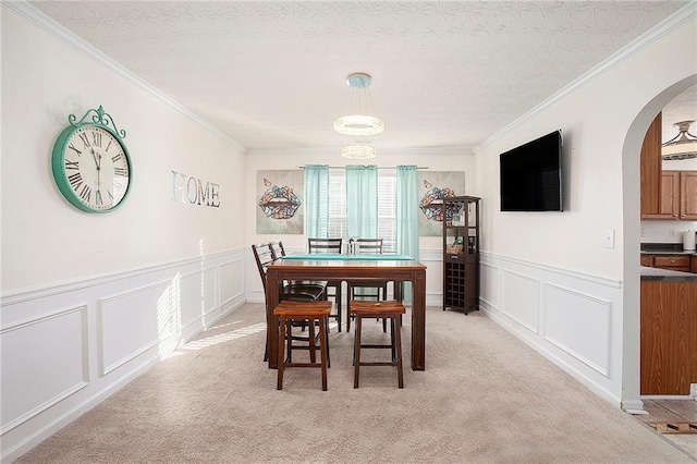 dining room featuring a textured ceiling, light colored carpet, and crown molding