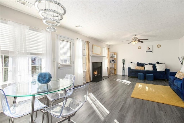 living room featuring a textured ceiling, ceiling fan with notable chandelier, and dark hardwood / wood-style floors