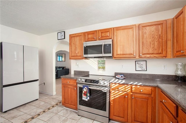 kitchen with light tile patterned floors, a textured ceiling, and stainless steel appliances