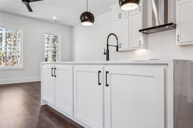 kitchen featuring wall chimney exhaust hood, decorative backsplash, baseboards, dark wood-style flooring, and hanging light fixtures