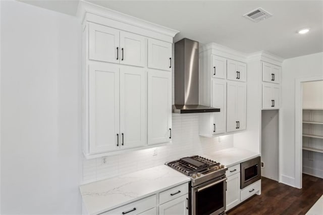 kitchen featuring visible vents, tasteful backsplash, appliances with stainless steel finishes, and wall chimney exhaust hood