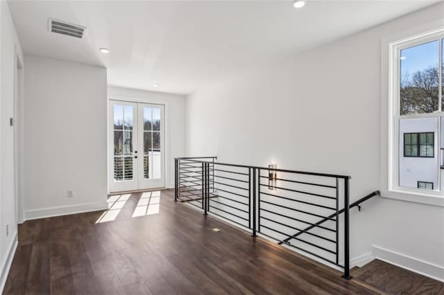 spare room with wood finished floors, a healthy amount of sunlight, visible vents, and baseboards