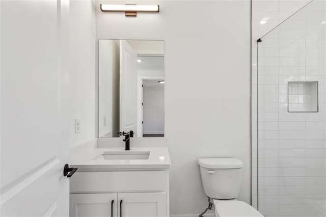 full bathroom featuring a tile shower, toilet, and vanity