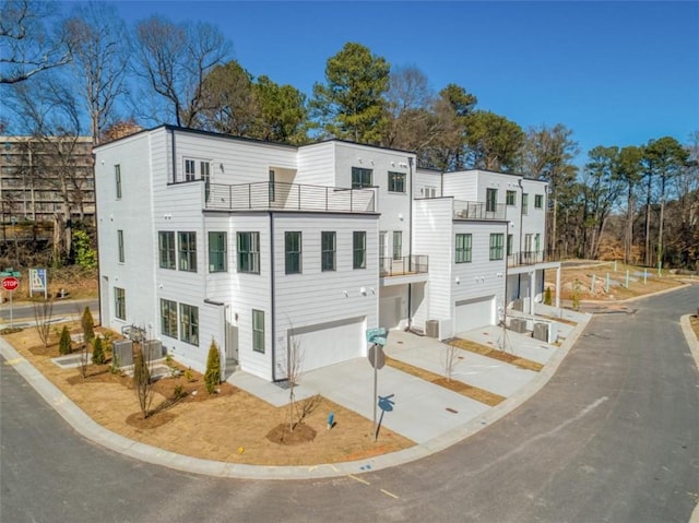 view of front of property featuring a balcony, cooling unit, a garage, and driveway