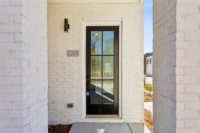 view of exterior entry featuring brick siding