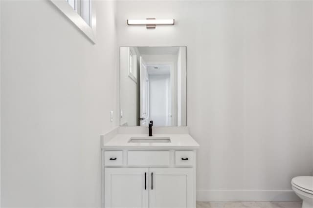 bathroom featuring vanity, toilet, baseboards, and marble finish floor