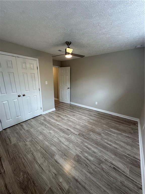 3967 Evelyn Dr, Powder Springs, GA 30127 - unfurnished bedroom featuring baseboards, wood finished floors, a closet, a textured ceiling, and a ceiling fan
