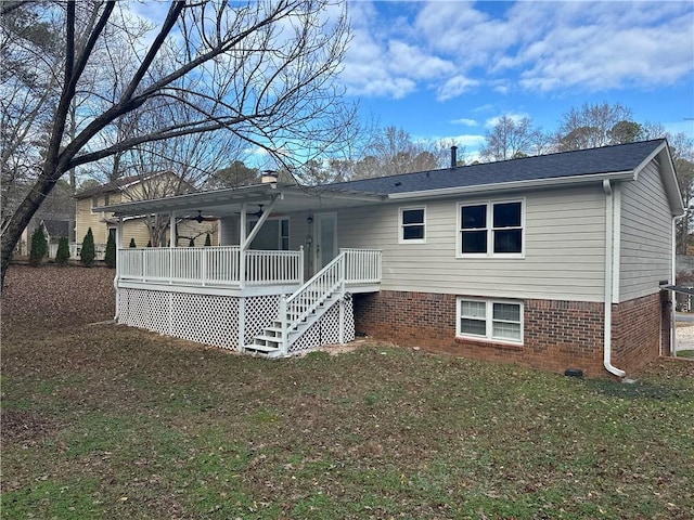 rear view of property with ceiling fan and a lawn